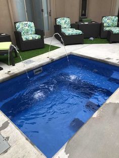 a blue swimming pool surrounded by lawn furniture and artificial grass in a backyard area with water running from the faucet