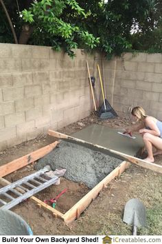 a woman kneeling down next to a pile of dirt in a backyard with a shovel