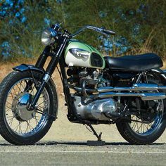 a green and white motorcycle parked on the side of a road next to some trees