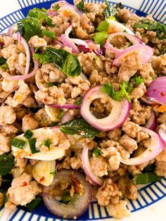 a blue and white plate filled with meat, onions, spinach and other vegetables