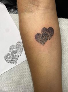 two fingerprints in the shape of hearts on a person's arm with a white envelope behind them