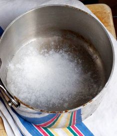 a metal pan sitting on top of a wooden cutting board next to a white towel