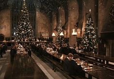 people sitting at long tables in a restaurant with christmas trees