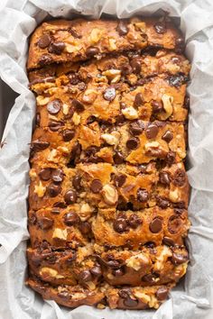 a loaf of bread with chocolate chips and nuts in it on top of white paper