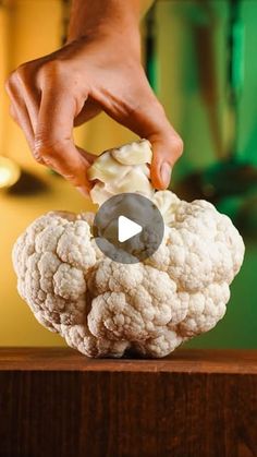 a person is placing something on top of a cauliflower