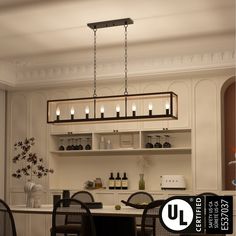 a dining room table and chairs with bottles on the shelves above it, in front of an open kitchen area