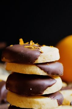 a stack of chocolate covered cookies next to an orange