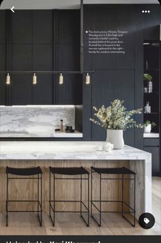 a kitchen with marble counter tops and stools in front of the island, surrounded by black cabinets