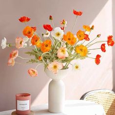 a white vase filled with lots of flowers on top of a table