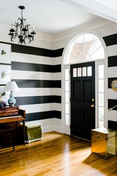 a black and white striped wall in a living room with a chandelier hanging from the ceiling