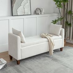 a white couch sitting on top of a wooden floor next to a potted plant