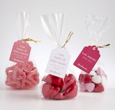 three bags filled with pink and white candies on top of a table next to each other