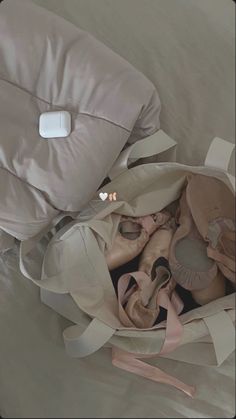 a pile of ballet shoes sitting on top of a bed next to a pillow and pillows