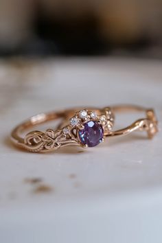 a gold ring with an amethorate and diamond accenting the band, sitting on a marble surface