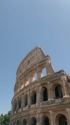 an old roman collise with people standing on the top floor and looking up into the sky