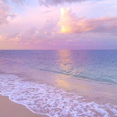 an ocean beach with waves coming in to shore and the sun shining on the water