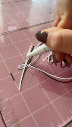 a person is holding a pair of scissors on a pink tile floor with wires attached to it