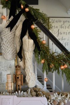 christmas decorations on the banisters and stairs in a house with pine cones, lights, stockings and garland