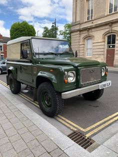 a green land rover is parked on the side of the road