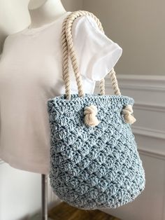 a blue crocheted bag hanging from a mannequin