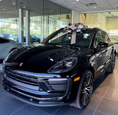 a black porsche cayen with a bow on it's hood in a showroom