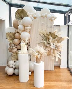 a table topped with balloons and vases filled with white flowers on top of a wooden floor