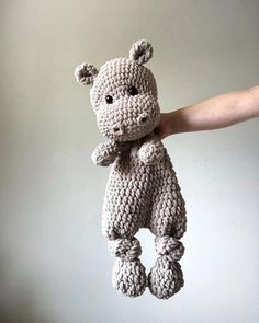 a crocheted teddy bear being held in the air by someone's hand