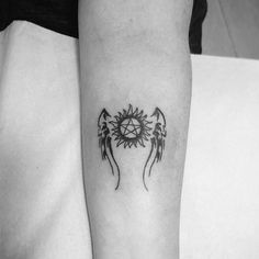 a black and white photo of an angel tattoo on the left arm with wings around it