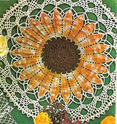 crocheted doily with orange flowers on green background and yellow roses in the foreground