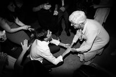 an older man and young woman dancing in a room with other people holding their hands