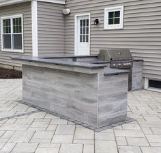 an outdoor kitchen made out of cinder blocks on a patio with a bbq grill in the middle