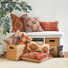 a bunch of pillows sitting on top of a white bench next to a potted plant