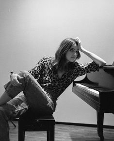 a woman sitting on top of a stool next to a piano