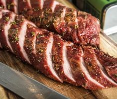 sliced meat sitting on top of a cutting board next to a knife