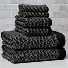 black towels stacked on top of each other in front of a white brick wall and floor