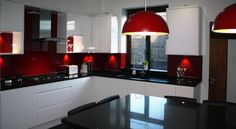 a kitchen with red lights hanging from the ceiling and black counter tops on the counters