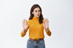 a woman in an orange sweater is holding her hands up to the side and making a stop sign