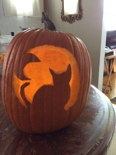 a carved pumpkin sitting on top of a table in front of a mirror with the shape of a cat