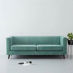 a blue couch sitting next to a potted plant on top of a white floor