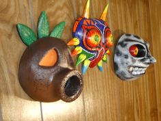 two clay skulls are sitting on the floor next to each other, one with an orange eye