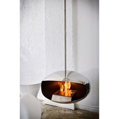 a modern fireplace with an open flame in the center and a white wall behind it