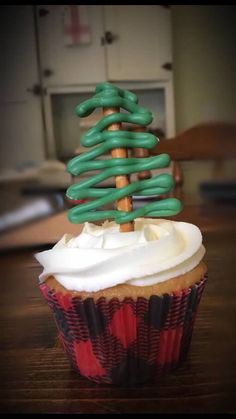 a cupcake decorated with green icing and a christmas tree on top is sitting on a table