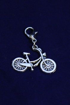 a silver charm with a bicycle on it's back end and a key chain attached to the clasp