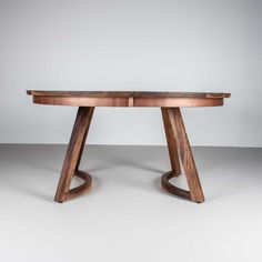 a wooden table sitting on top of a white floor next to a gray wall in the background