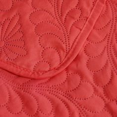 an orange quilted blanket with holes in the middle and a red pillow behind it