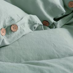 two buttons are attached to the back of a green comforter with linens on it