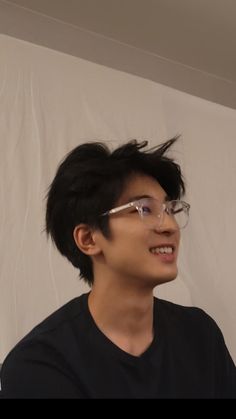 a young man wearing glasses is smiling for the camera