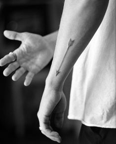 a person with a small arrow tattoo on their arm