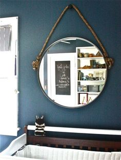 a mirror hanging on the wall above a sink in a room with blue walls and white trim