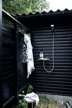 an outdoor shower in the middle of a wooden decked area with black shutters